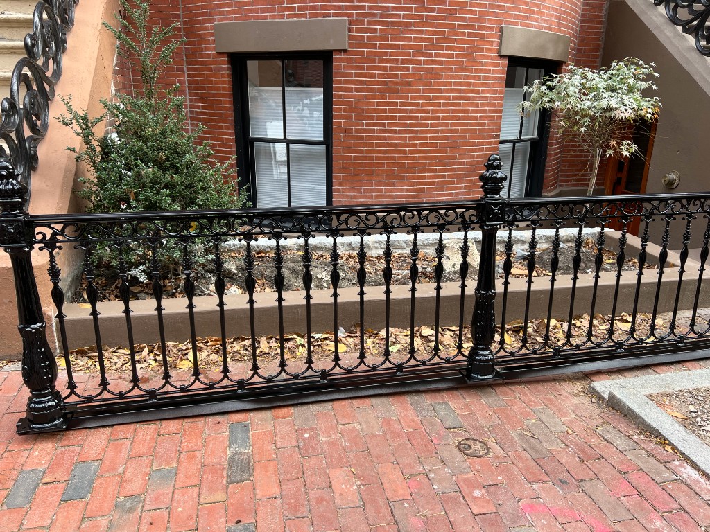 Decorative black iron fence along a brick walk, ornamental ironwork