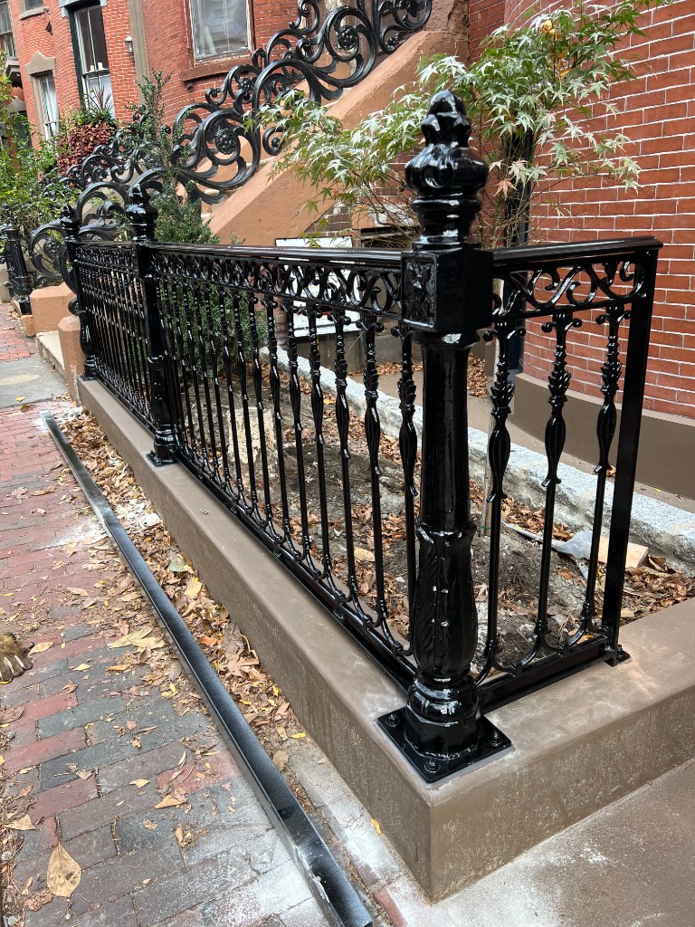 Ornamental iron fence and stair railing at a brick residence