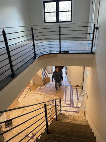 Curved black railing with horizontal bars on an upper landing