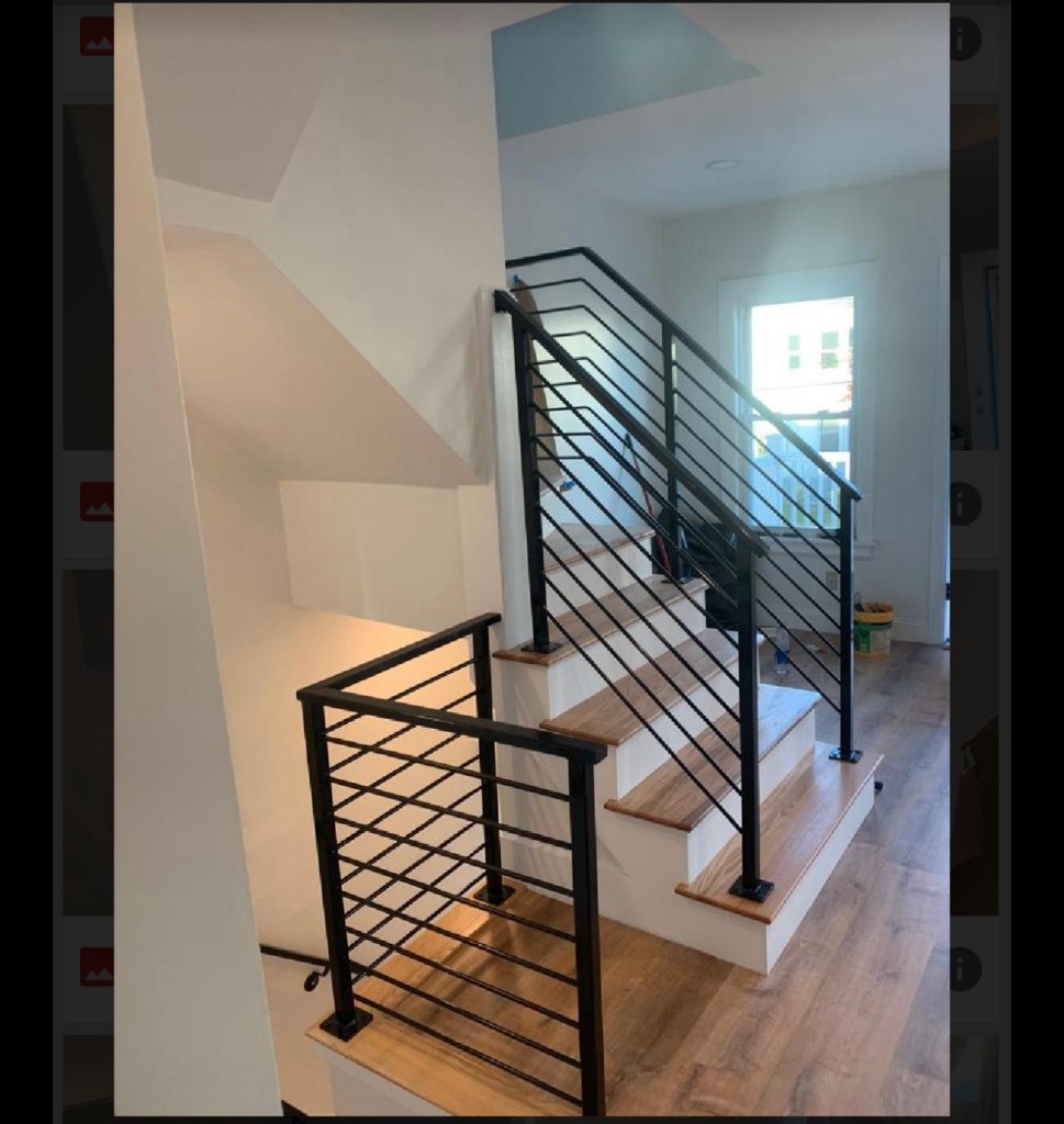 Black stair railing with a square grid panel at the lower landing