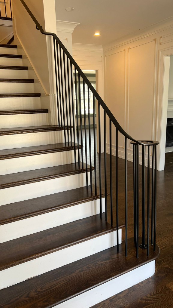 Black iron handrail with vertical balusters on a wood stair