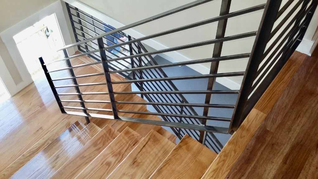 Looking down an interior stair with a black horizontal bar railing