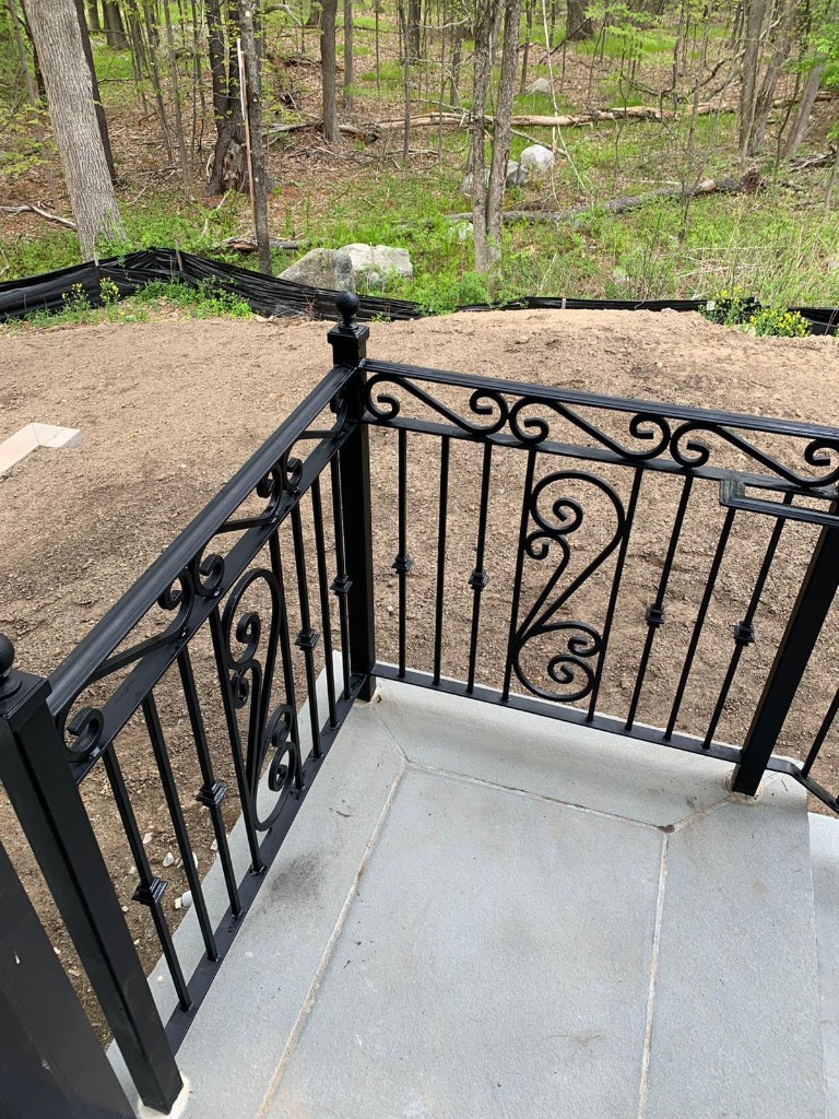 Ornamental iron porch railing at a wooded landing