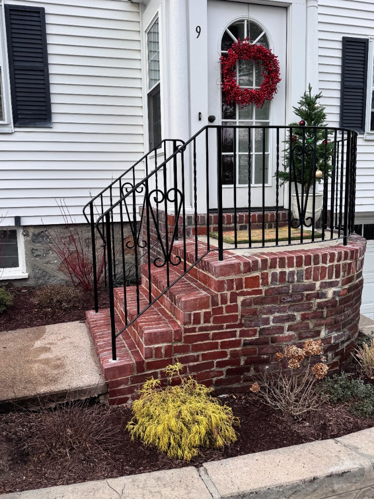 Black iron railing along a brick entry
