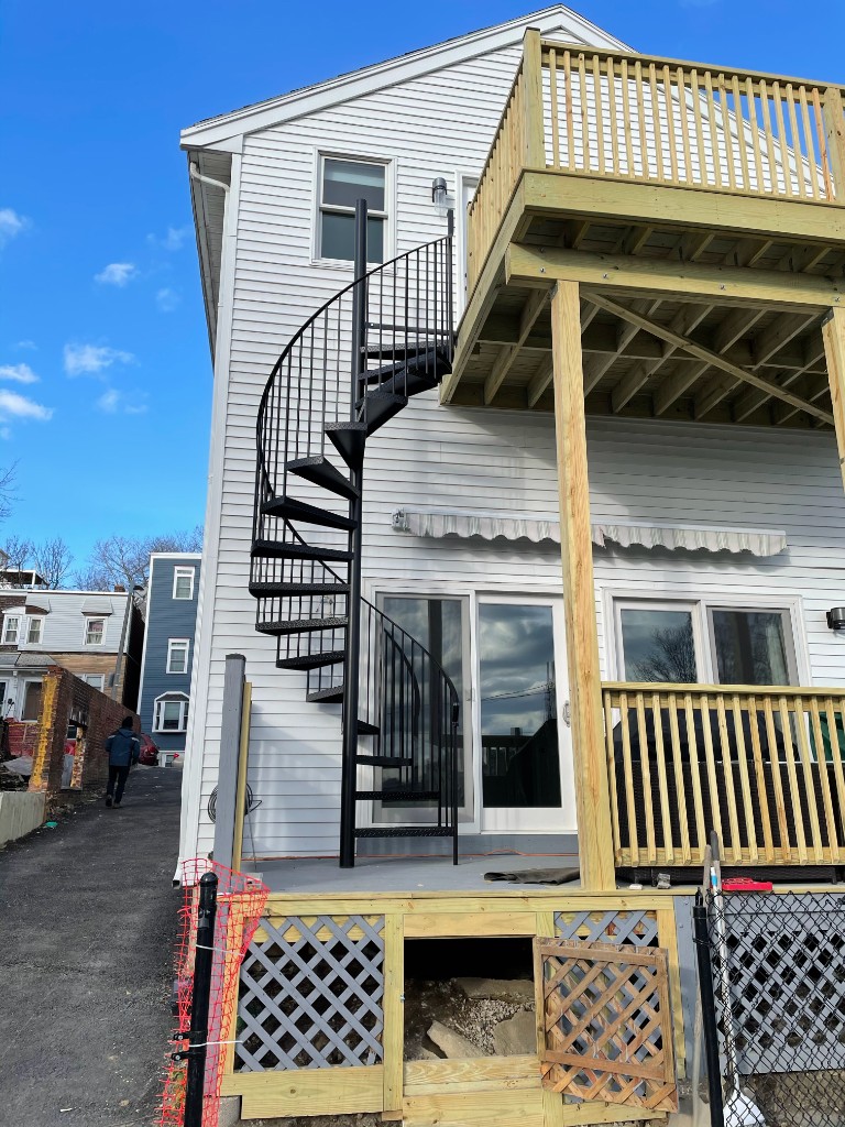 Exterior black iron spiral staircase with diamond-plate treads, deck-to-deck Massachusetts install