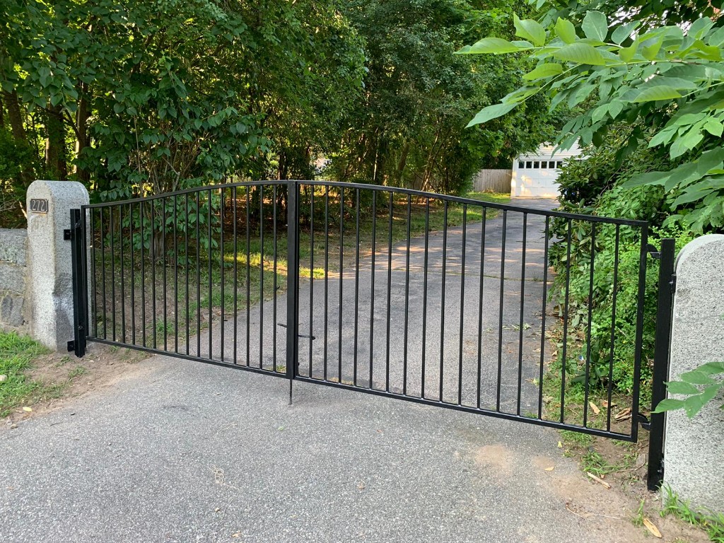 Double-swing black iron driveway gate with stone pillars, Massachusetts install